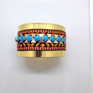 Gold tone cuff with embroidery and blue stone details.